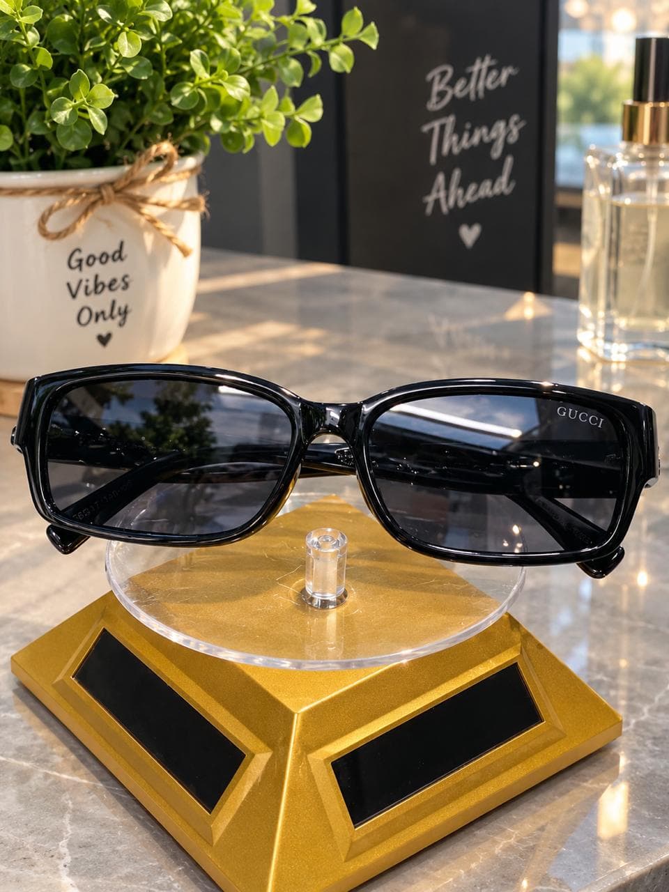 Black square sunglasses displayed on a gold stand